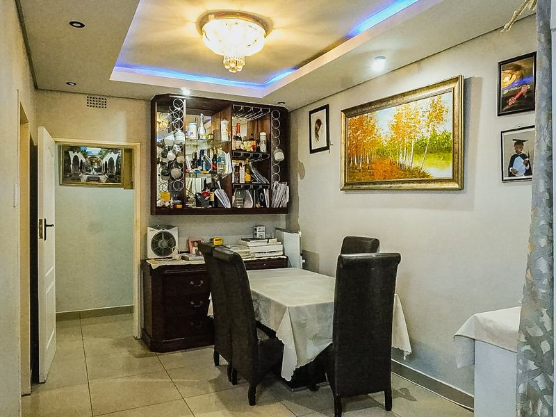 Dining area featuring tiled flooring, a recessed ceiling with cove lighting, and a built-in display cabinet.