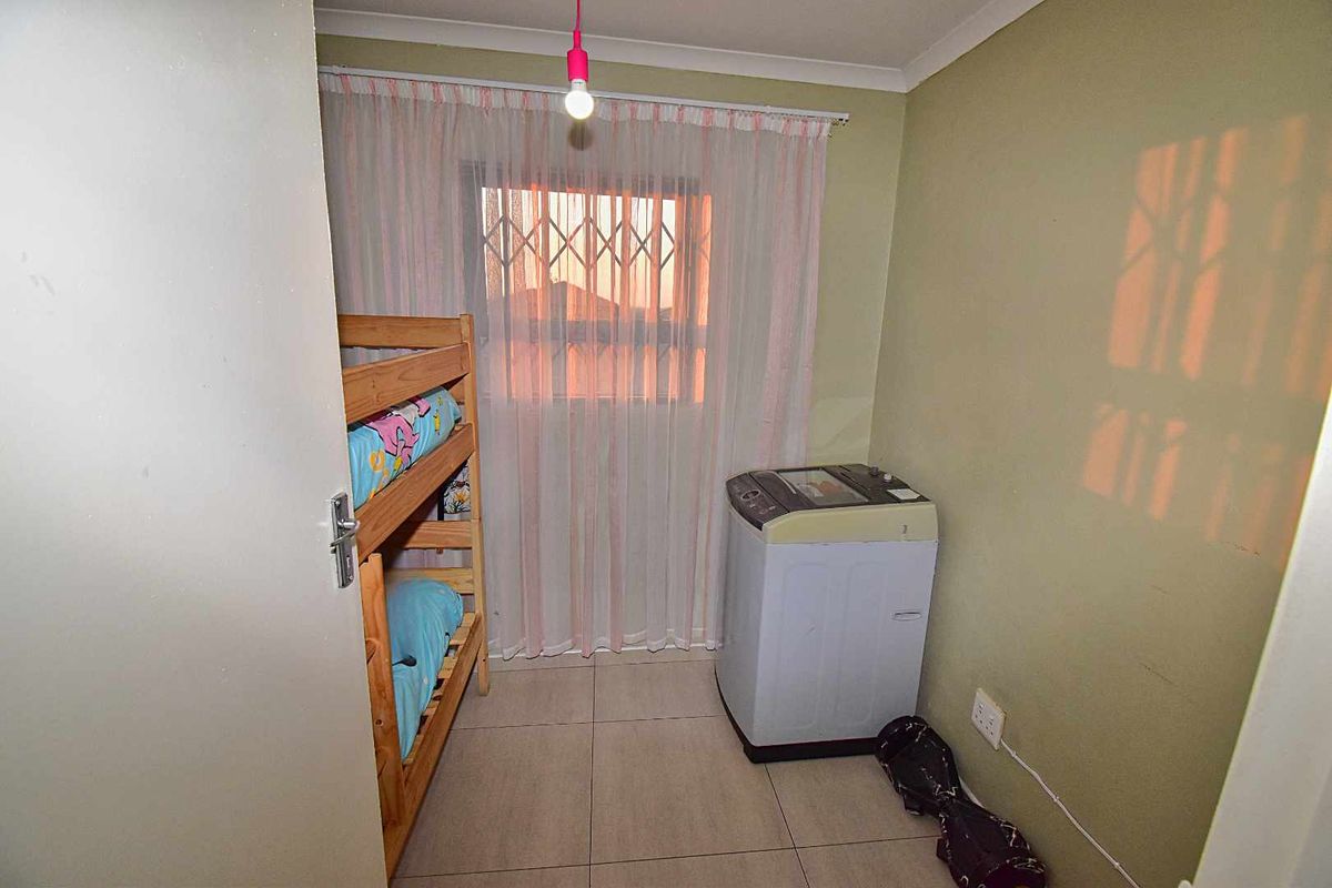 A functional bedroom space featuring tiled flooring, a security gate on the window, and a central light fixture.