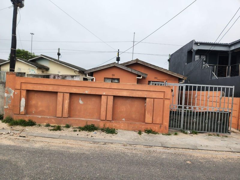 Front exterior view of a residential property featuring a perimeter wall, metal security gate, and tiled roof structure.