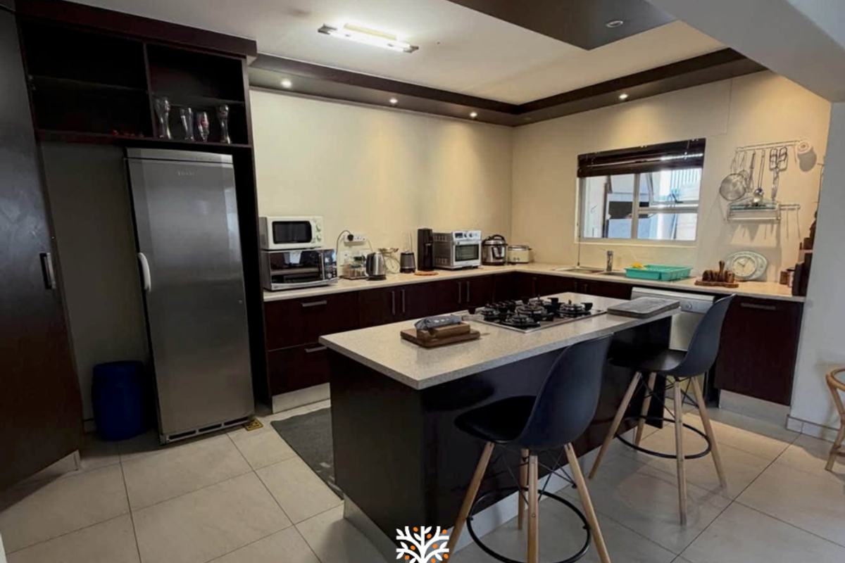 Modern kitchen featuring dark wood cabinetry, a central island with a gas hob, stone countertops, and recessed ceiling lighting.