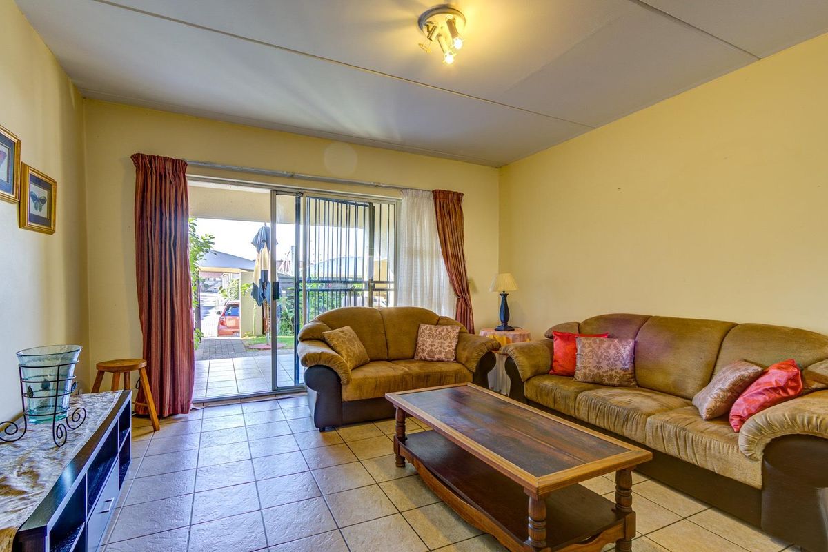 A living room featuring tiled flooring and a sliding glass door providing direct access to an outdoor patio area.