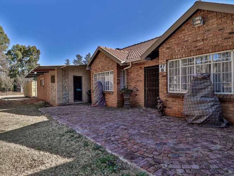 Front exterior view of a brick-faced small holding property featuring a cobblestone paved entrance area and secure access.