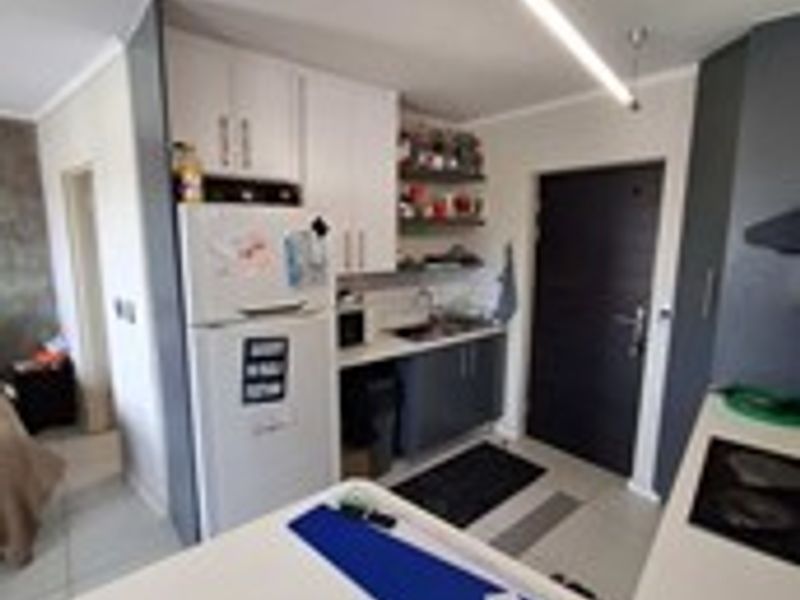 A compact kitchen featuring built-in cabinetry, a functional countertop, and a sink, providing essential preparation space within the apartment.