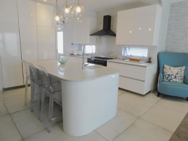 Modern kitchen featuring a central island with quartz countertops, sleek white cabinetry, gas stove, and high-end finishes throughout.