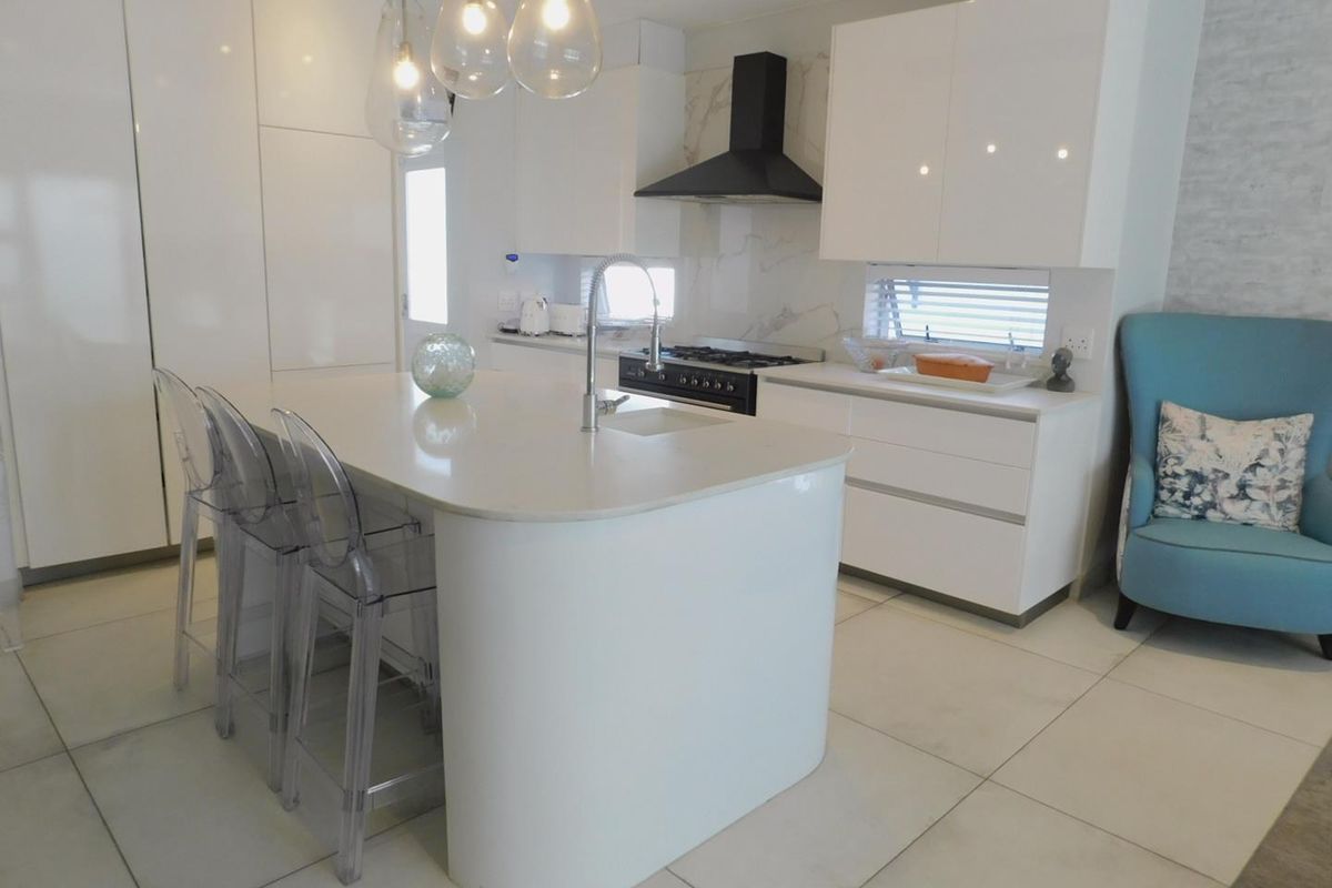 Modern kitchen featuring a central island with quartz countertops, sleek white cabinetry, gas stove, and high-end finishes throughout.