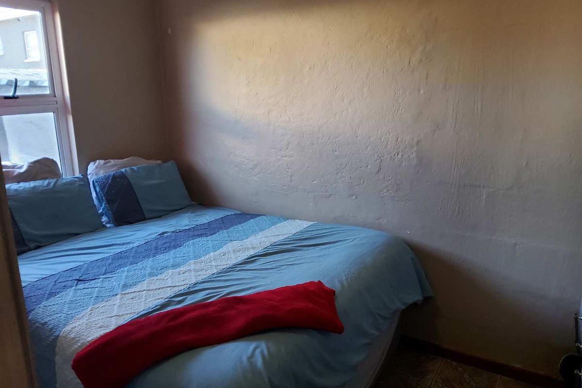 A compact bedroom featuring tiled flooring and a window, providing a functional sleeping space.