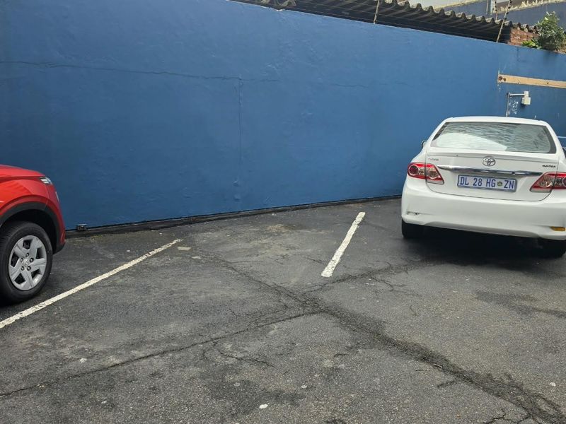 An outdoor parking area featuring asphalt paving and a painted boundary wall.