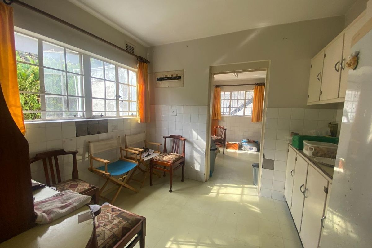 A dated kitchen featuring original cabinetry, tiled splashbacks, and multi-pane windows, offering significant potential for a modern renovation and layout update.