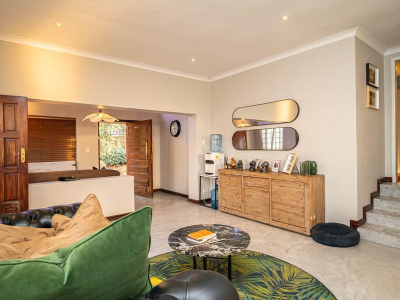Spacious living area featuring tiled flooring, recessed downlighting, and a staircase leading to an upper level, with direct access to an outdoor space.