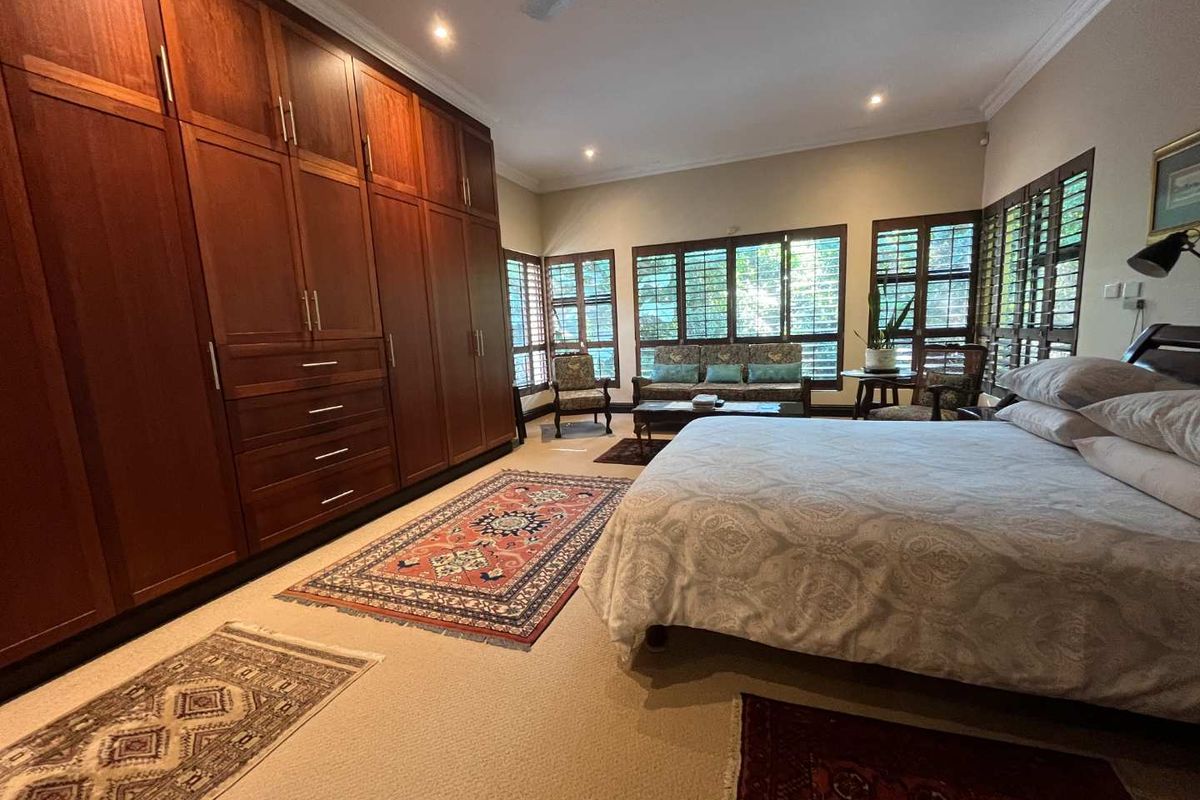 Spacious bedroom featuring extensive floor-to-ceiling built-in wooden cabinetry, recessed downlighting, and plantation-style window shutters.