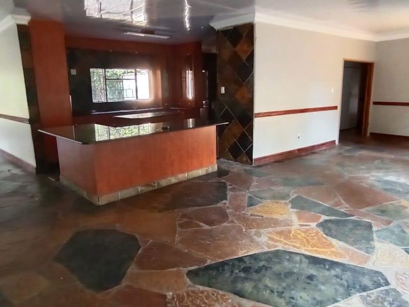 Spacious open-plan living area featuring unique stone flooring, a central kitchen island with granite countertops, and neutral wall finishes.