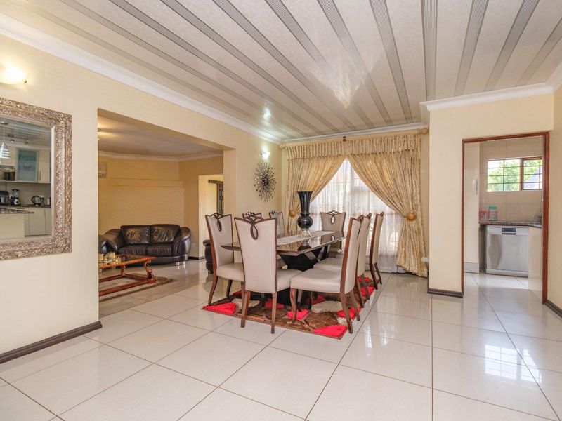Open plan dining and living area featuring tiled flooring and a coved ceiling, with an adjacent kitchen visible through the doorway.