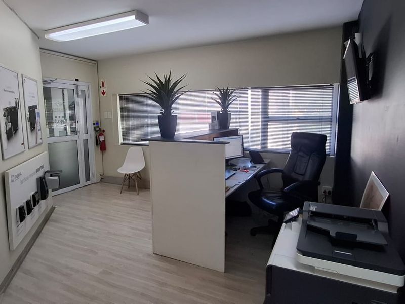 A functional office reception area featuring a built-in desk, laminate flooring, and natural light through venetian blinds.
