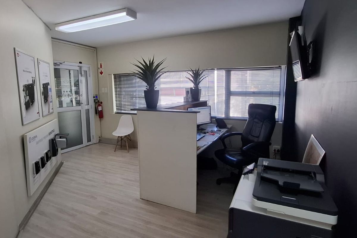 A functional office reception area featuring a built-in desk, laminate flooring, and natural light through venetian blinds.
