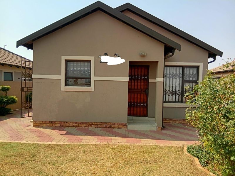 Front elevation of a single-story house featuring a tiled roof, brick paving, and secure entrance with security gate.