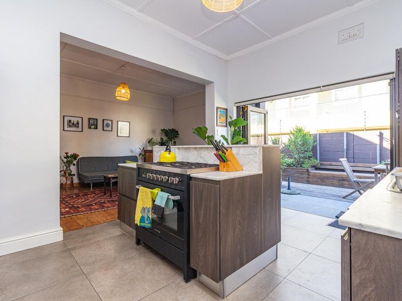 Open-plan kitchen featuring a central island with a gas stove, stone countertops, and seamless flow to an outdoor patio area.