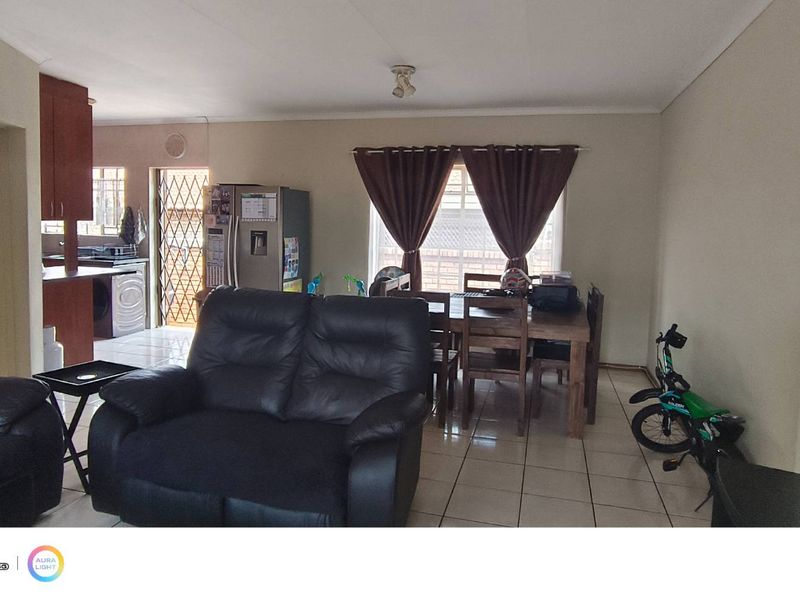 Open-plan living and dining area featuring tiled flooring and an adjacent kitchen space with built-in cabinetry.