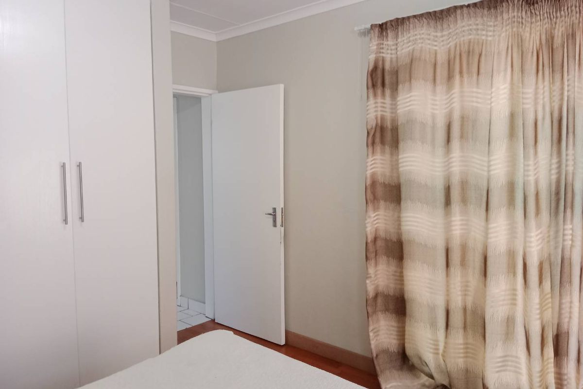A bedroom featuring built-in cupboards, laminate flooring, and neutral wall finishes, providing a clean and functional living space.