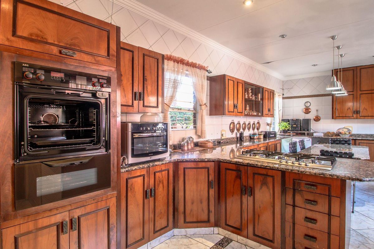 Spacious kitchen featuring traditional timber cabinetry, granite countertops, built-in oven, and gas hob, offering ample storage and workspace.