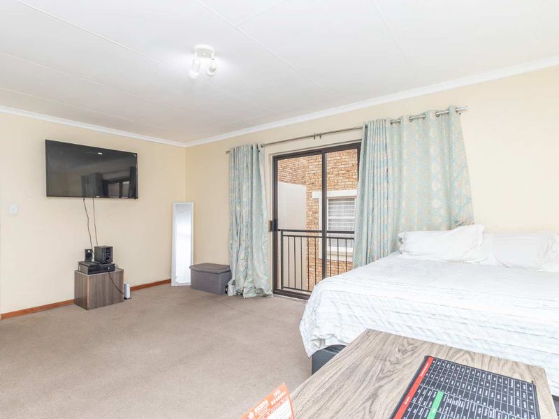A spacious bedroom featuring carpeted flooring and a sliding glass door providing access to a private balcony.