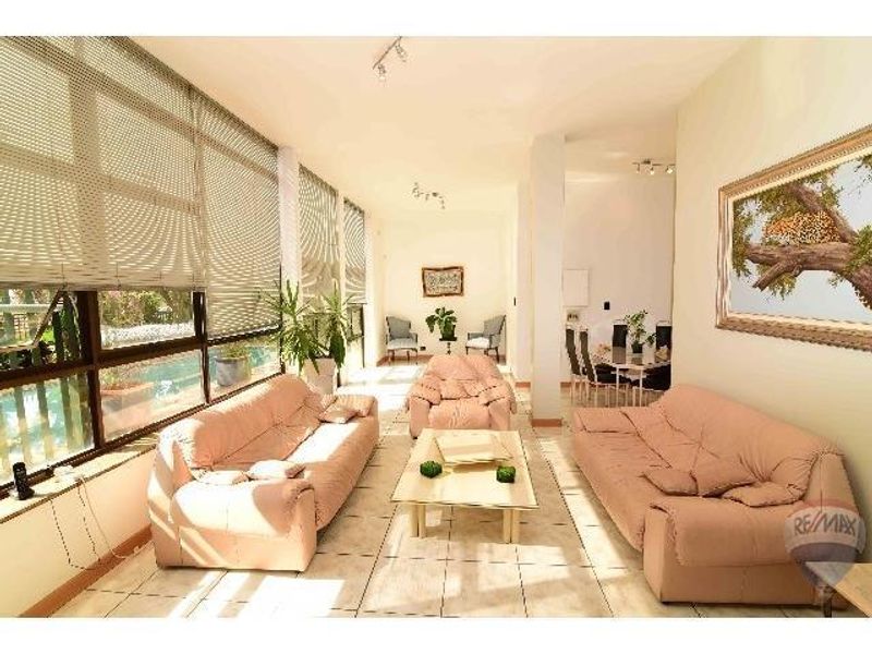 Spacious open-plan living area featuring large windows with pool views, tiled flooring, and integrated lighting, creating a bright and airy atmosphere.