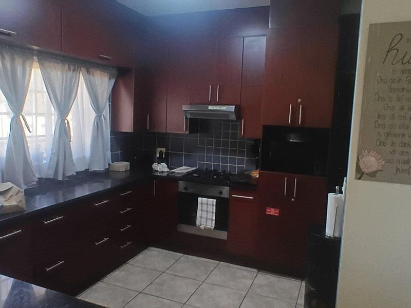 A functional kitchen featuring dark wood cabinetry, granite countertops, a gas hob, and an integrated oven with a tiled backsplash.