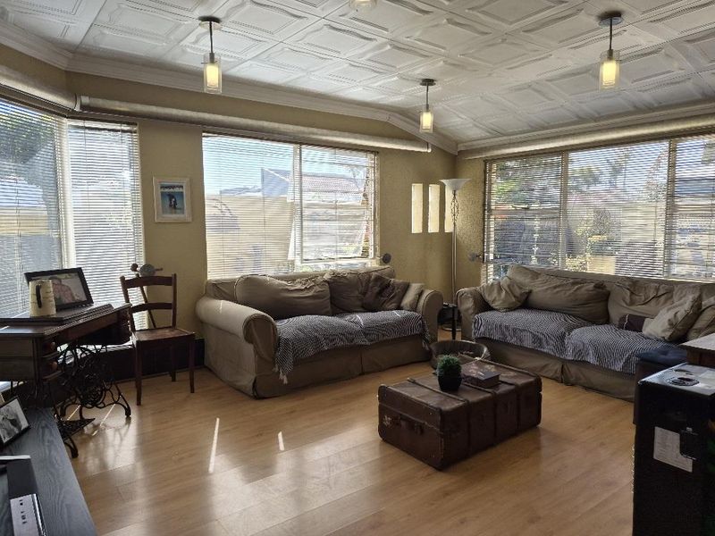 Spacious living room featuring laminate flooring, a decorative coffered ceiling, and large windows that provide ample natural light.