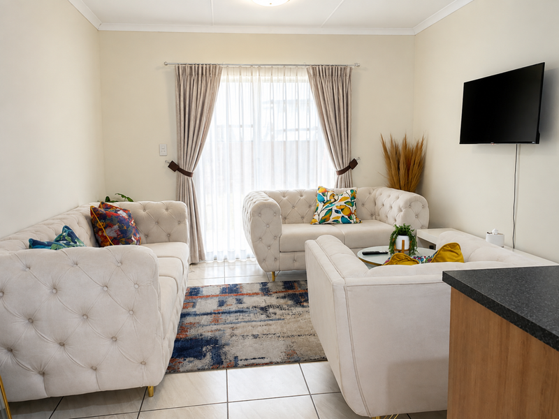 A well-maintained living room featuring tiled flooring, neutral walls, and a sliding glass door providing access to the exterior.