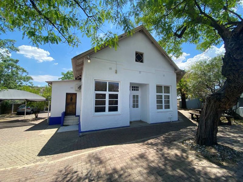 Front view of a white office building featuring a gabled roof, paved driveway, and a covered carport area.