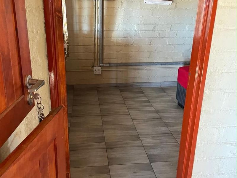 A utility space featuring tiled flooring and exposed brick walls with surface-mounted electrical infrastructure.