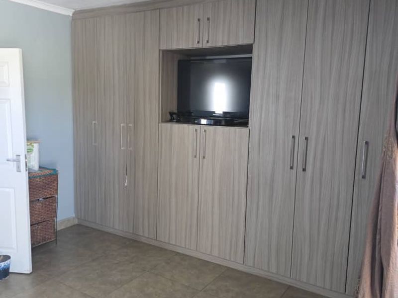 A bedroom featuring extensive built-in cabinetry with a central media nook, tiled flooring, and recessed ceiling lighting.
