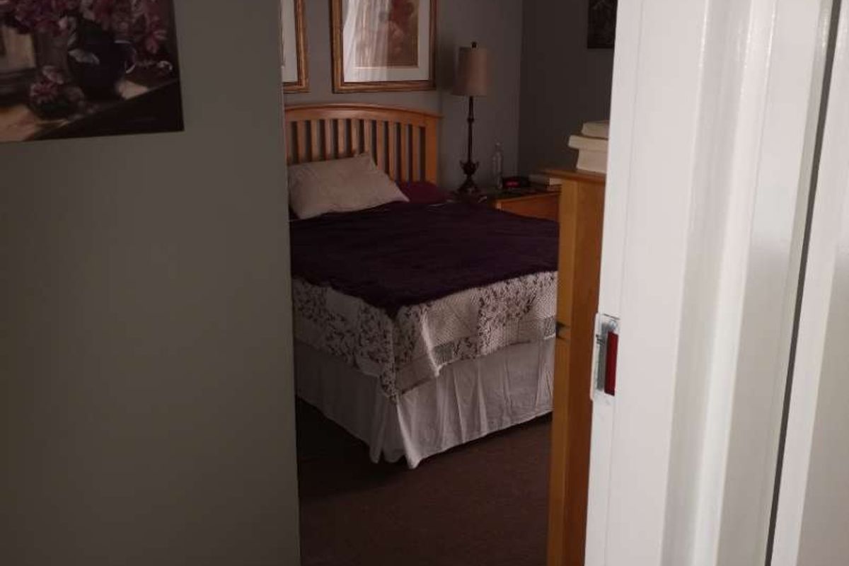 A view into a bedroom featuring carpeted flooring and neutral wall tones, accessed through a standard interior doorway.
