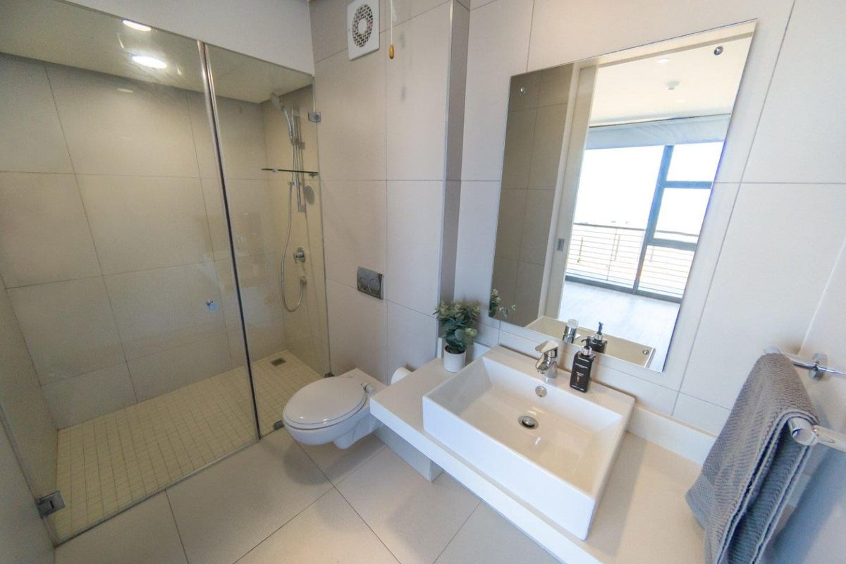 Modern bathroom featuring a glass-enclosed shower, wall-mounted toilet, and a contemporary vessel sink with a large wall-mounted mirror.