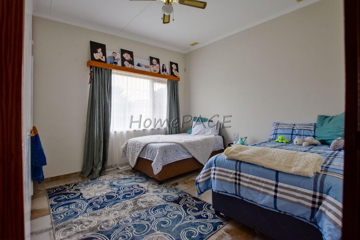 A bedroom featuring tiled flooring and a ceiling fan, with a large window providing natural light.