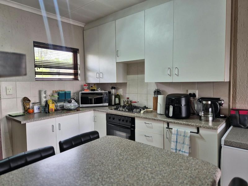 A functional kitchen featuring white cabinetry, laminate countertops, a gas hob, and a built-in oven with tiled backsplash.