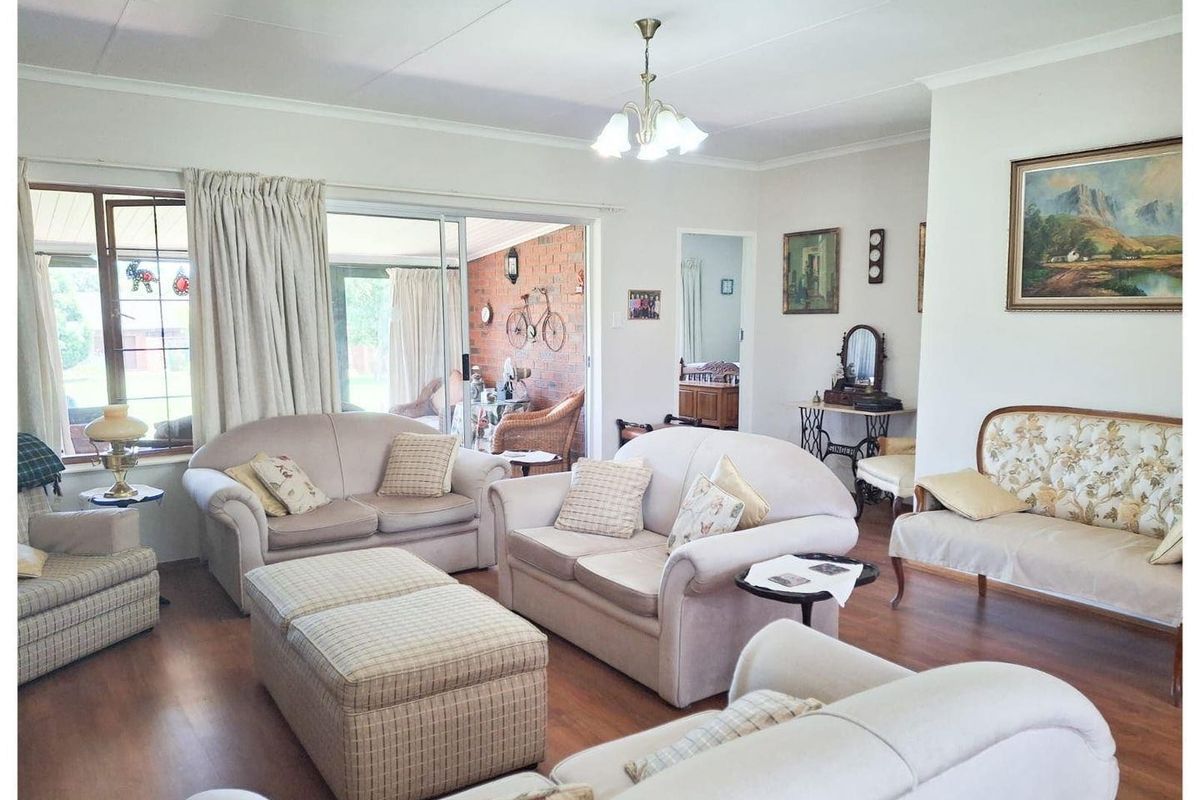 A spacious living room featuring laminate flooring, sliding glass doors leading to a covered patio, and neutral wall finishes.