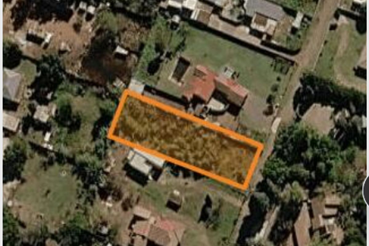 An aerial view of a vacant residential land parcel highlighted in orange, situated within an established suburban neighborhood.