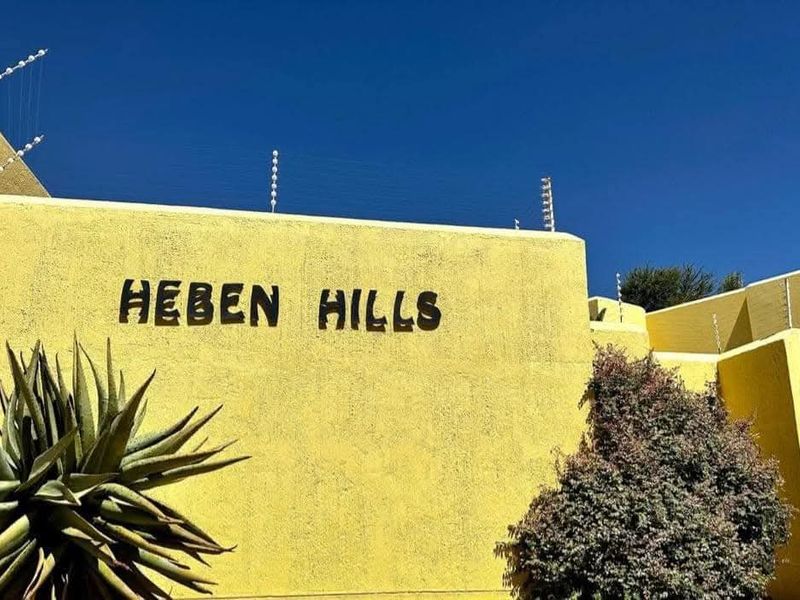 Exterior view of the Heben Hills complex entrance, featuring yellow stucco walls and installed electric security fencing.