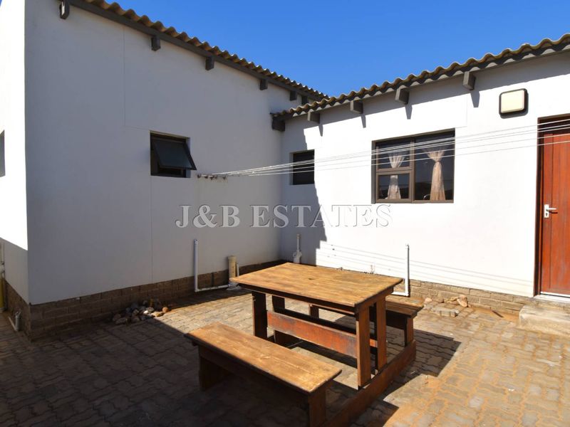 A rear courtyard area featuring paved flooring, external plumbing connections, and a washing line, providing a functional outdoor space.