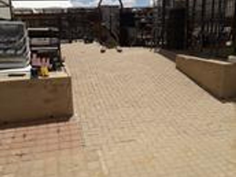 An industrial outdoor paved yard area featuring metal fencing and retaining walls, suitable for storage or operational use.