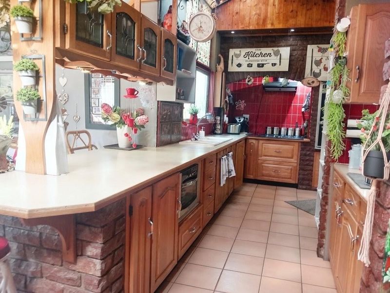 A rustic-style kitchen featuring wooden cabinetry, exposed brick accents, tiled backsplash, and integrated appliances, offering a warm and traditional aesthetic.