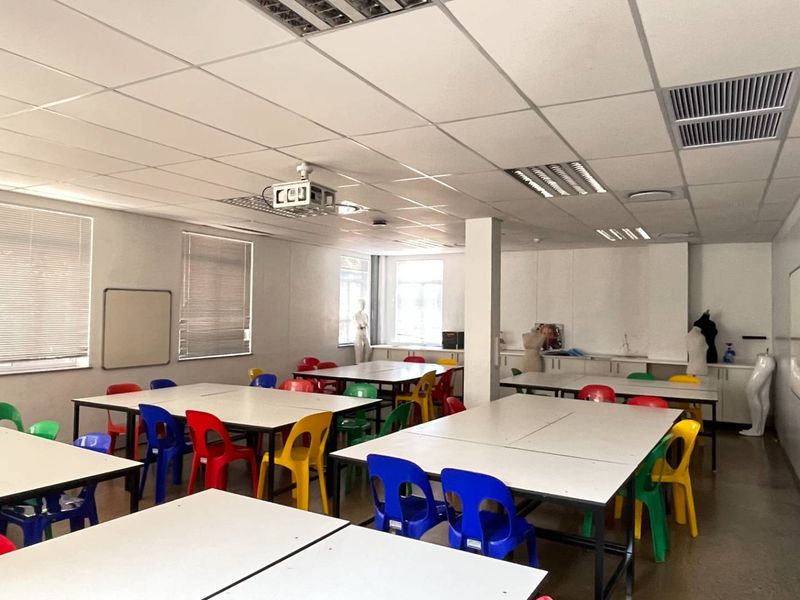 Spacious office or training room featuring a suspended ceiling, recessed lighting, air conditioning, and built-in cabinetry, suitable for collaborative work or educational purposes.