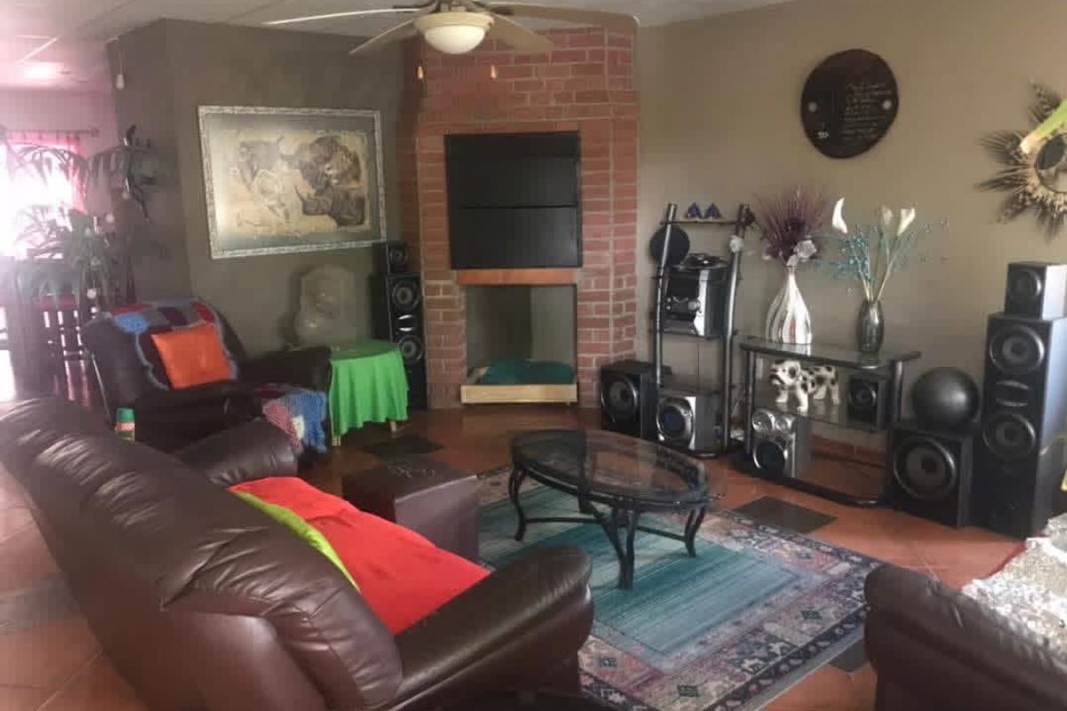 A living room featuring a central brick fireplace, ceiling fan, and tiled flooring, offering a cozy space for relaxation.