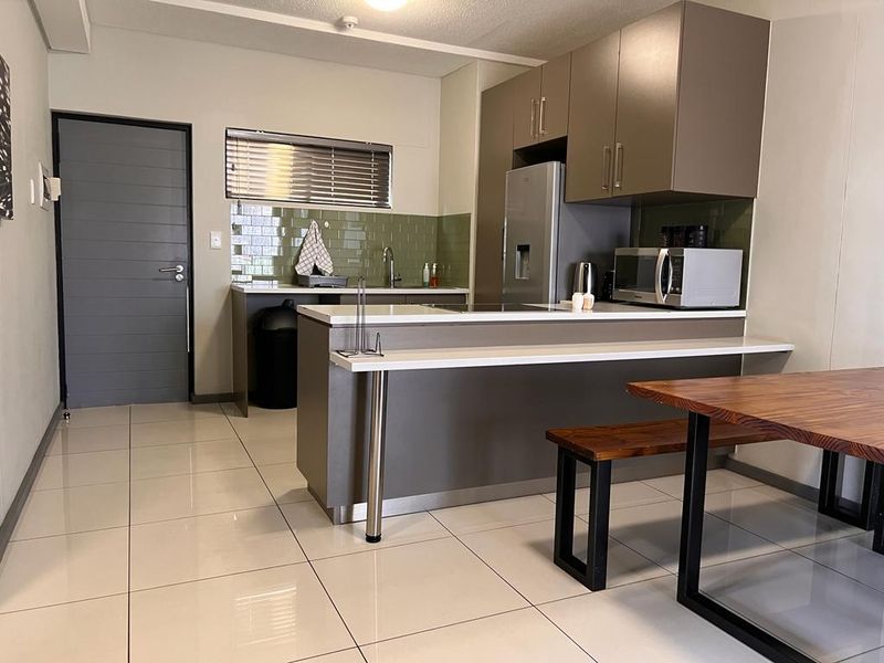 Modern kitchen featuring sleek cabinetry, a tiled backsplash, a breakfast bar, and tiled flooring, providing a functional and contemporary cooking space.