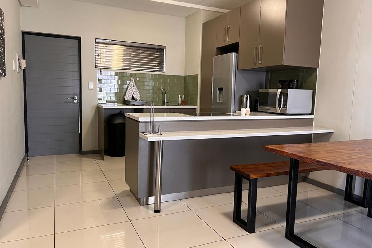Modern kitchen featuring sleek cabinetry, a tiled backsplash, a breakfast bar, and tiled flooring, providing a functional and contemporary cooking space.
