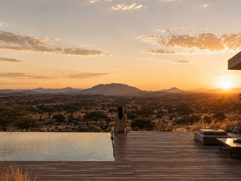 A stunning infinity pool and timber deck overlooking a vast landscape at sunset, featuring modern architectural design and seamless integration with the natural environment.