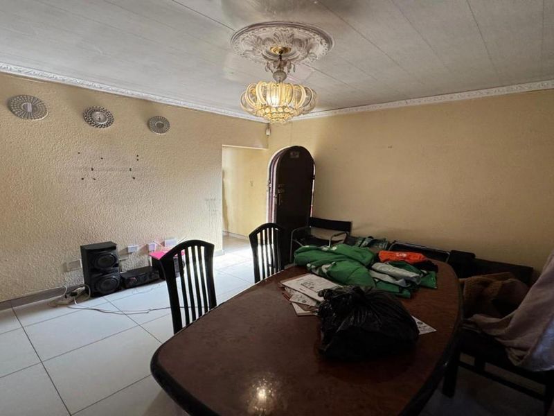 Dining room featuring tiled flooring, decorative ceiling rose, and cornice detailing, with an arched doorway leading to adjacent living spaces.