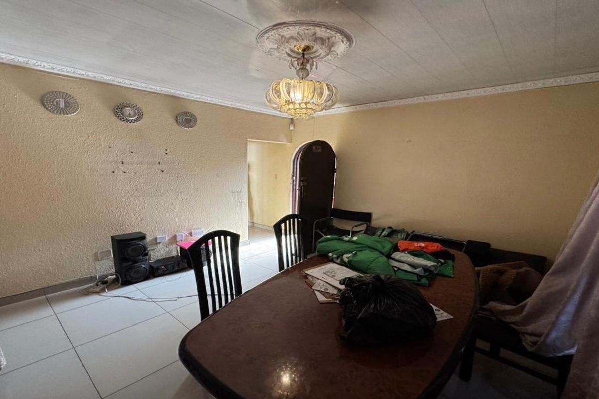 Dining room featuring tiled flooring, decorative ceiling rose, and cornice detailing, with an arched doorway leading to adjacent living spaces.