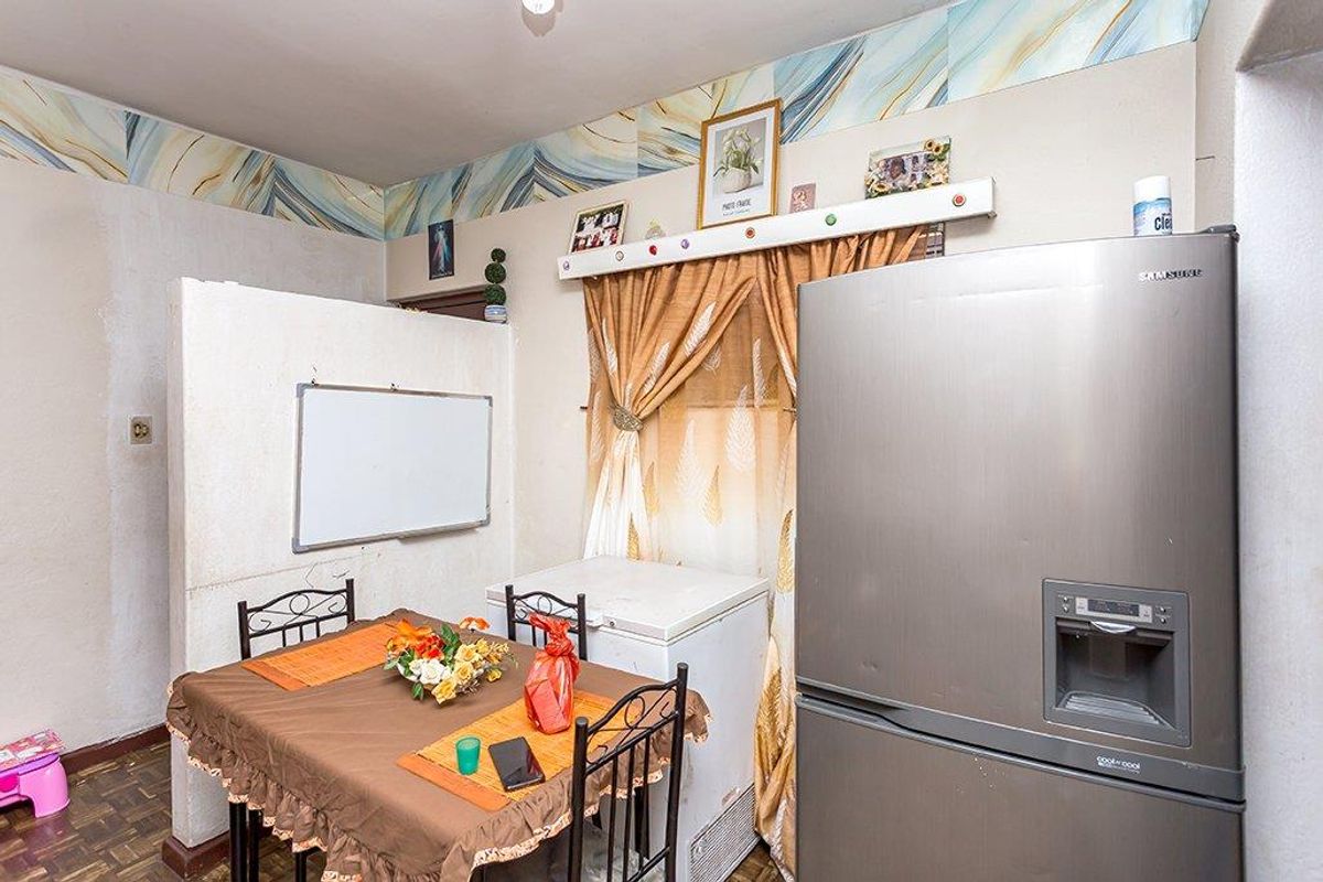 A kitchen area featuring parquet flooring and a decorative wallpaper border, currently utilized as a combined dining and utility space.