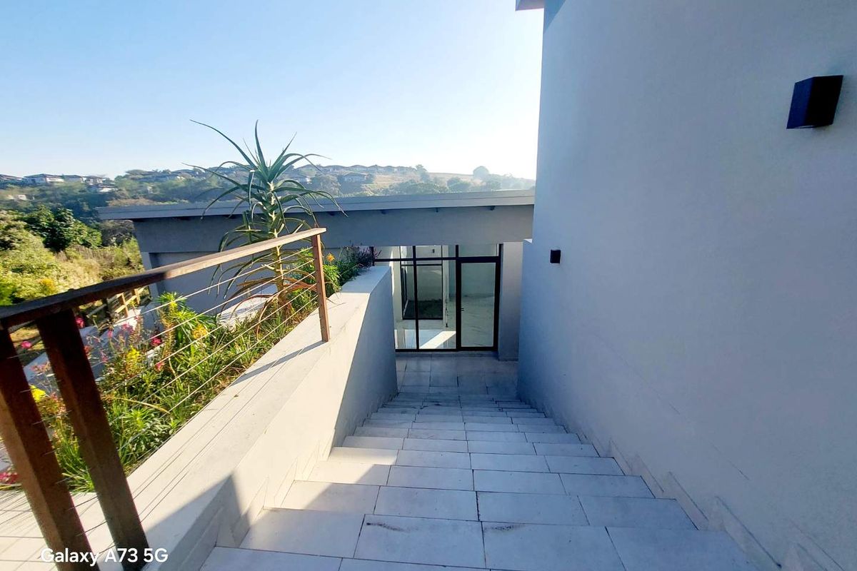 An outdoor staircase with modern tiled steps and a metal railing leading down to a glass-paneled entrance area.